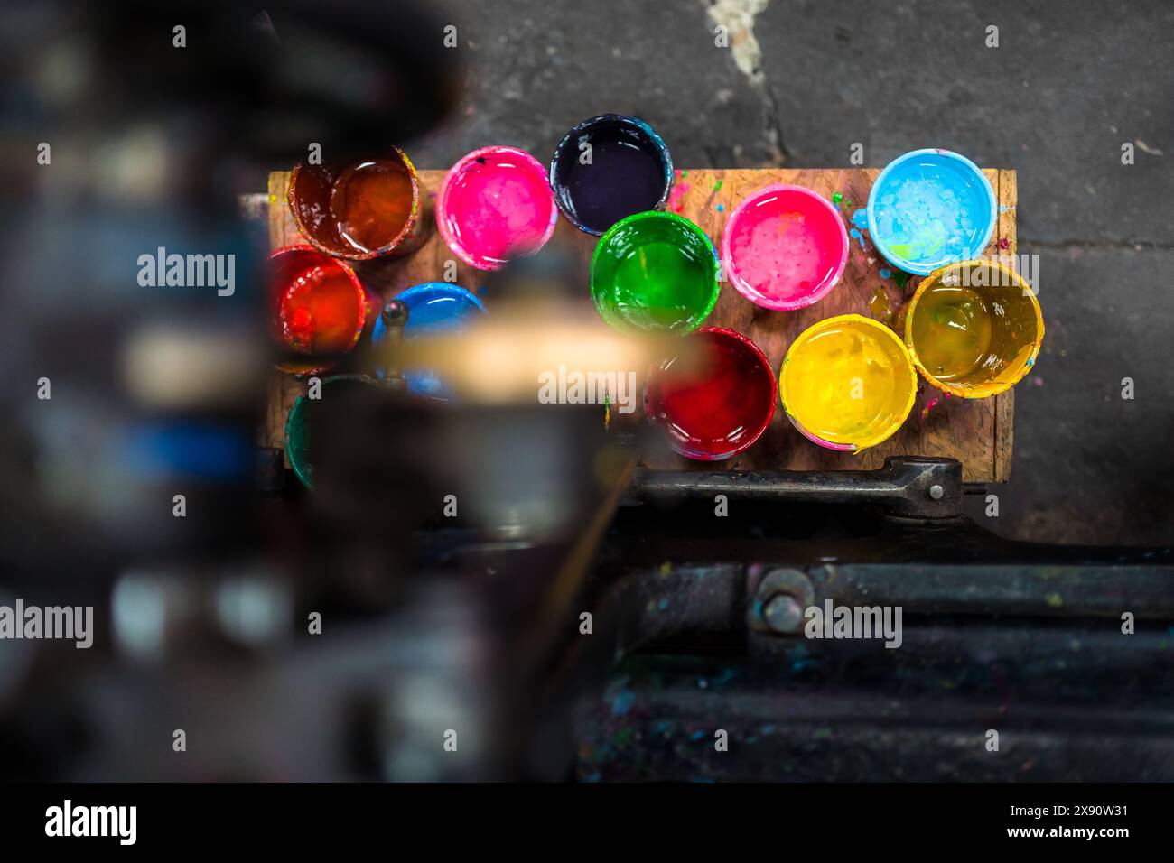 I secchi di inchiostri da stampa sono collocati sotto la storica macchina per tipografia in un'officina di stampa a Cali, Colombia. Foto Stock