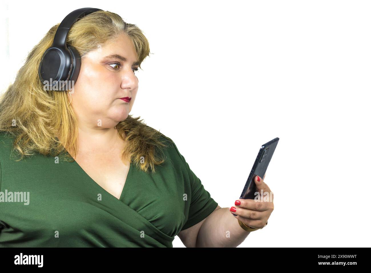 Questa fotografia cattura una donna bianca caucasica di mezza età con obesità leggera, immersa nel mondo digitale attraverso il suo smartphone Foto Stock
