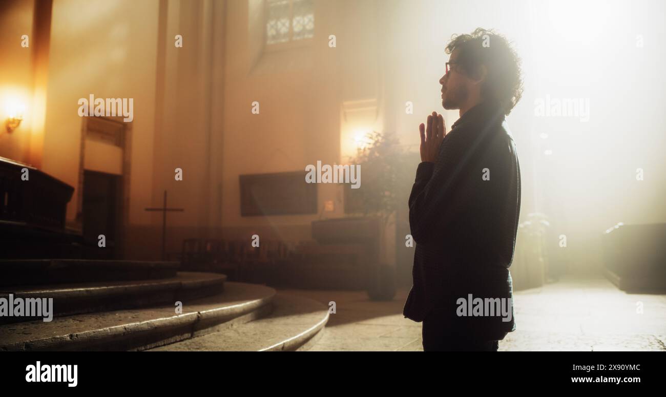 Uomo cristiano che si mette in ginocchio davanti all'altare e inizia a pregare in una Chiesa. Egli cerca una guida dalla sua fede religiosa e Spiritualità. Immagine del cristianesimo e della fede in Dio Foto Stock