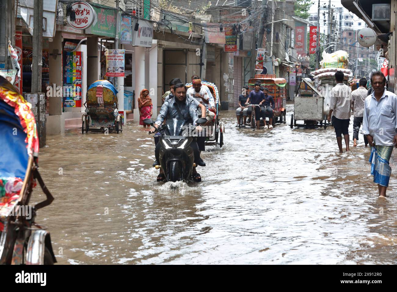 Dhaka, Bangladesh - 28 maggio 2024: I veicoli cercano di guidare attraverso una strada allagata; le forti piogge causate dal ciclone Remal hanno causato il disboscamento dell'acqua in vari rami Foto Stock