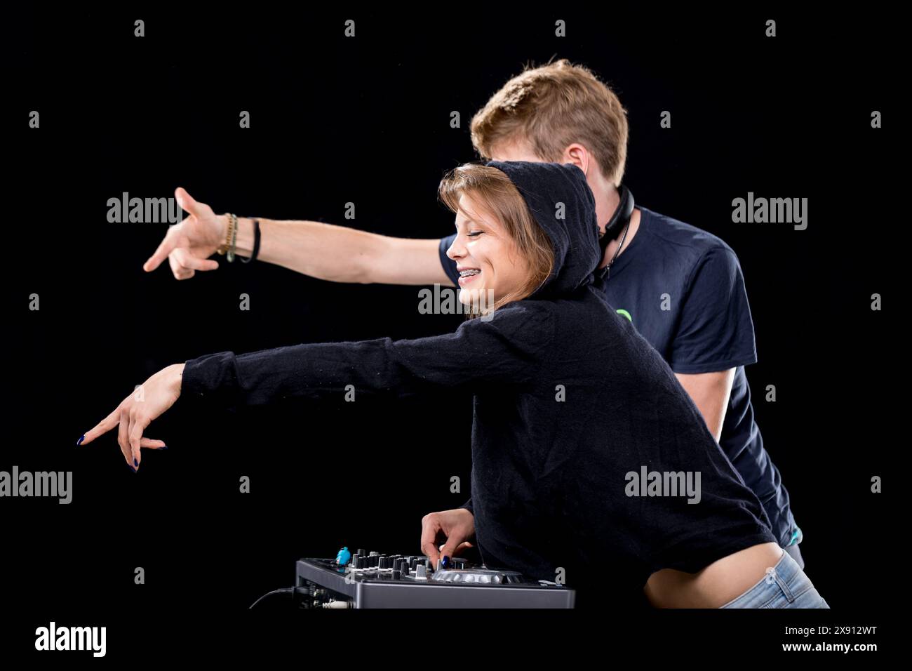 I DJ, completamente immersi nelle loro performance, sorridono e gestiscono il mixer. La donna in una felpa con cappuccio e l'uomo in una t-shirt sono evidenziati Foto Stock