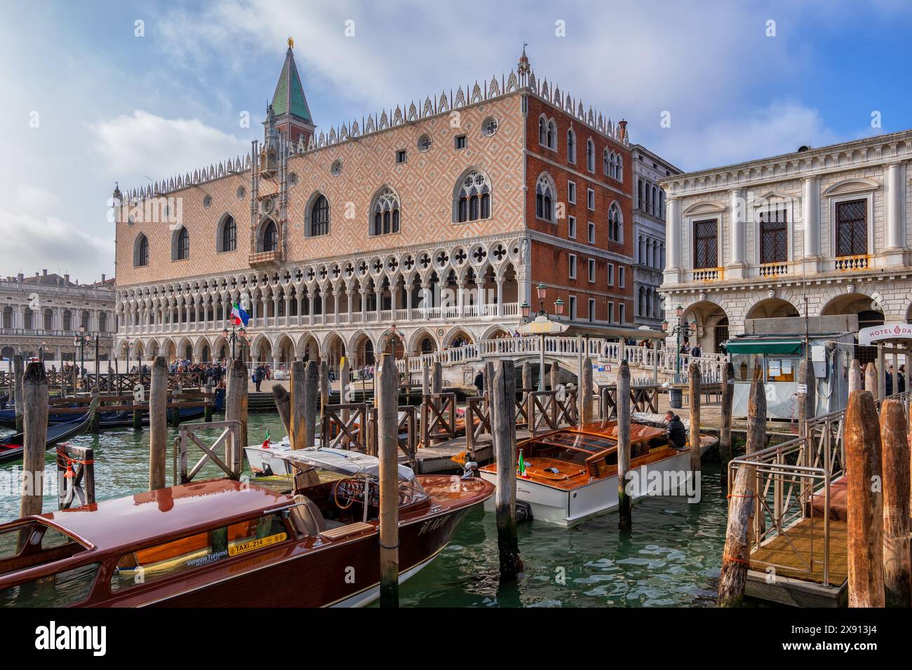 La città di Venezia in Italia, il Palazzo Ducale, le barche dei taxi d'acqua e il Ponte della paglia sul lungomare di Riva degli Schiavoni. Foto Stock