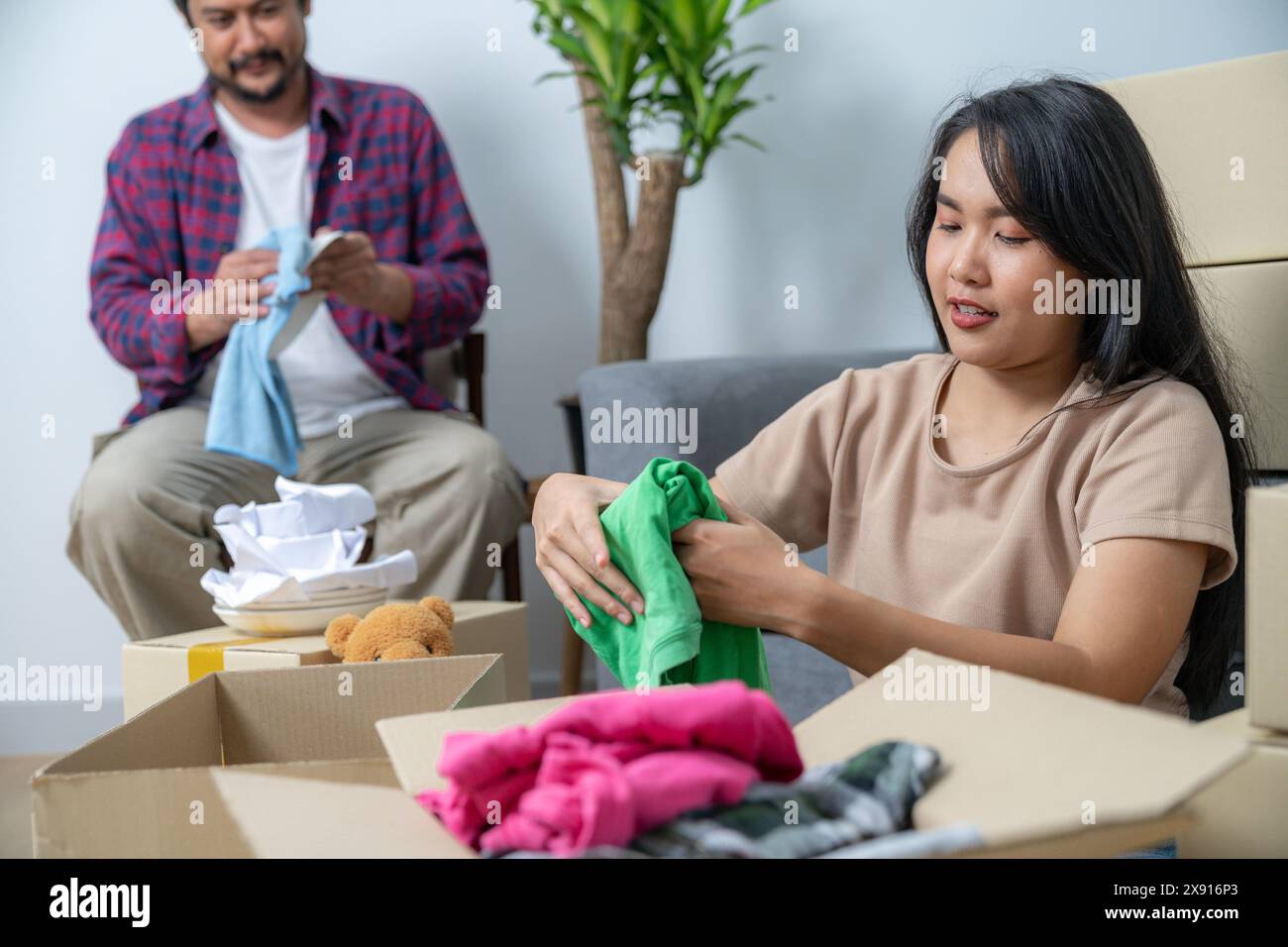 La giovane coppia si sta aiutando a vicenda a mettere in valigia oggetti per la casa per prepararsi a trasferirsi nella loro nuova casa Foto Stock