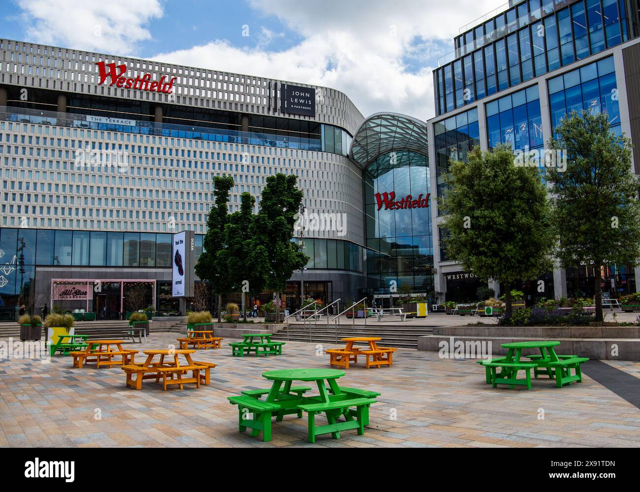 plaza all'aperto con tavoli da picnic verdi davanti all'ingresso del complesso commerciale Westfield sotto un cielo nuvoloso Foto Stock