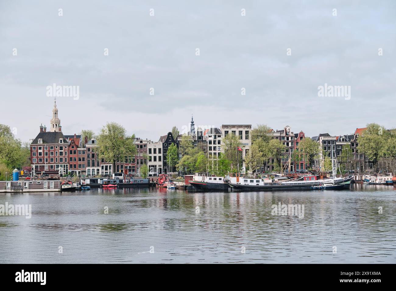 Paesi Bassi, Amsterdam - 10 aprile 2024: Riva del fiume Amstel e paesaggio urbano del lungomare di Amsterdam Foto Stock