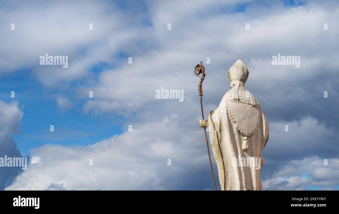 Religione cristiana e spiritualità. Antica statua del Vescovo o del Papa con crosier e mitra contro il cielo celeste Foto Stock