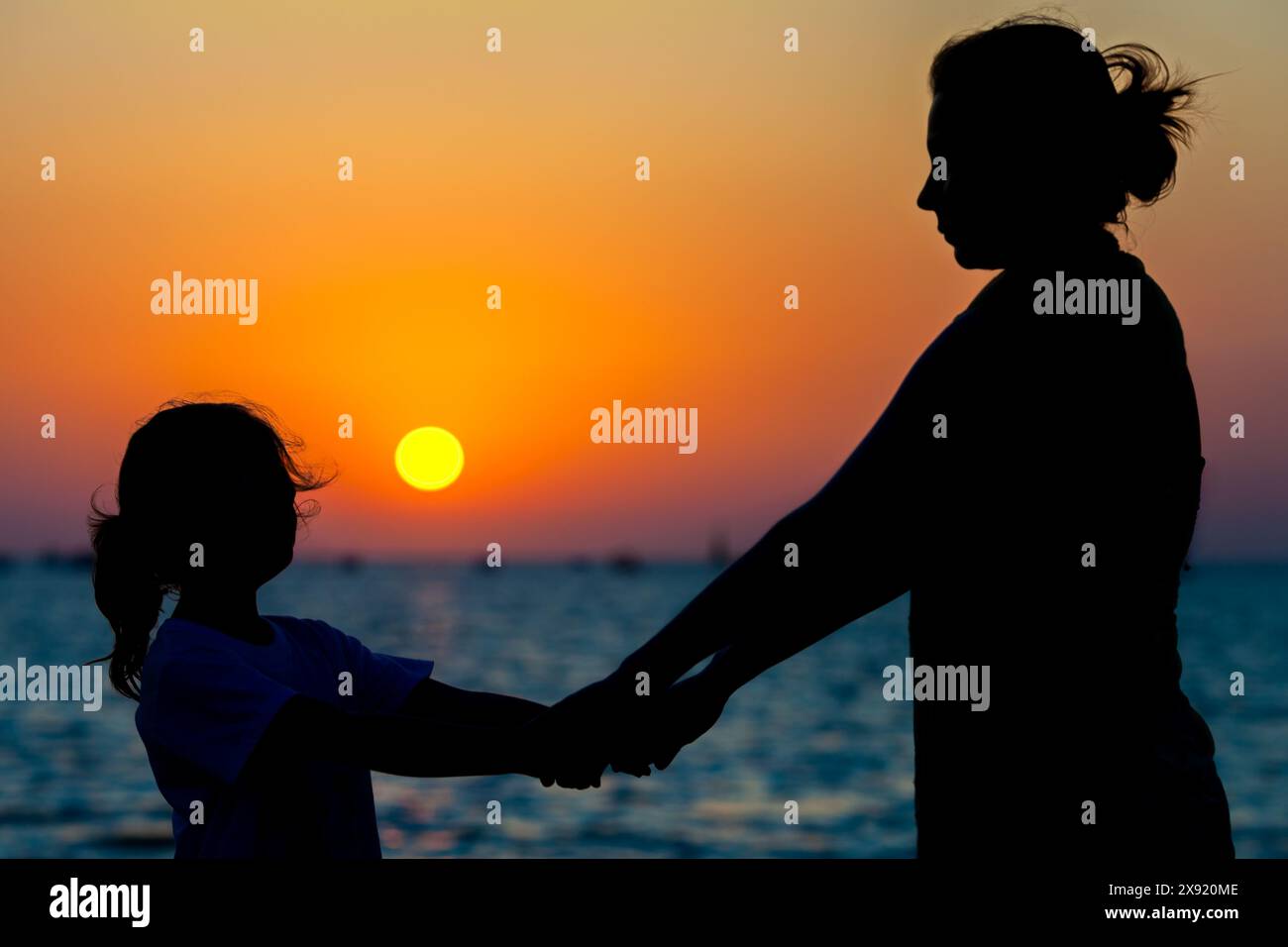 Una madre e sua figlia si tengono per mano mentre si godono un tramonto a Sanlucar de Barrameda Beach, Cadice, Spagna. Foto Stock