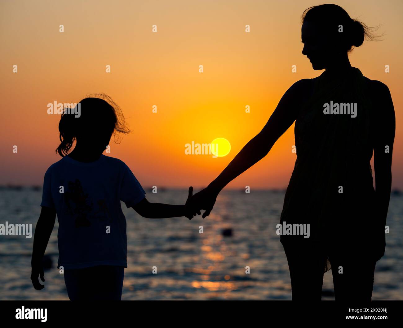 Una madre e sua figlia si tengono per mano mentre si godono un tramonto a Sanlucar de Barrameda Beach, Cadice, Spagna. Foto Stock