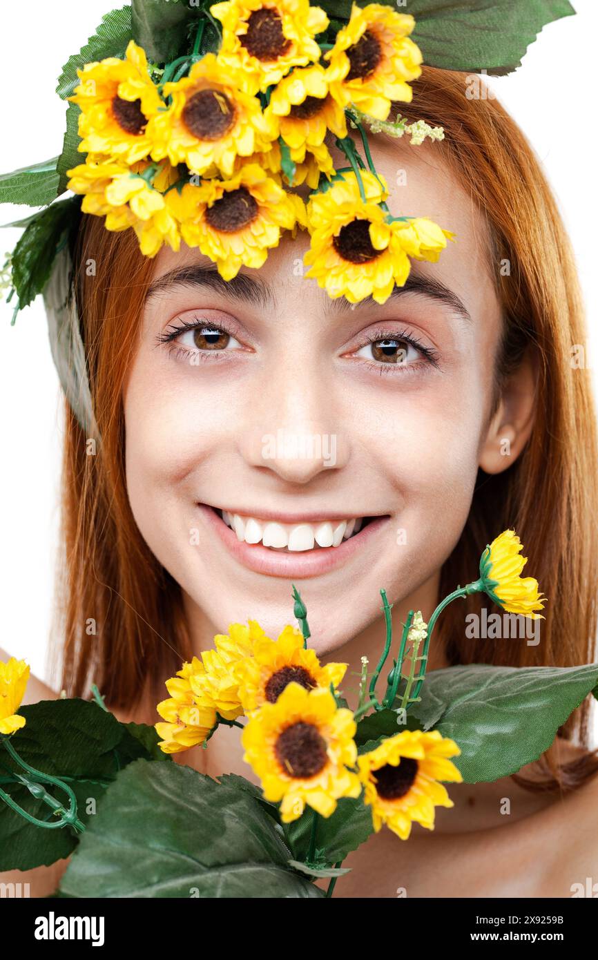 Ritratto di una giovane donna felice che indossa una fascia e un bouquet di girasole, che irradia gioia e freschezza su uno sfondo chiaro. Foto Stock