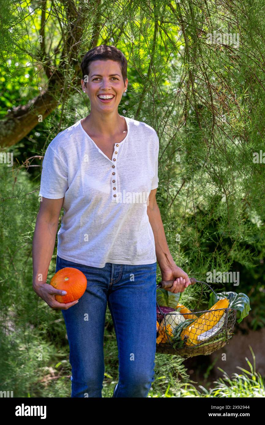 Giovane donna, vista frontale, con in mano un cesto pieno di verdure ritratto a mezza lunghezza di una donna con la raccolta dall'orto 016643_043 Foto Stock