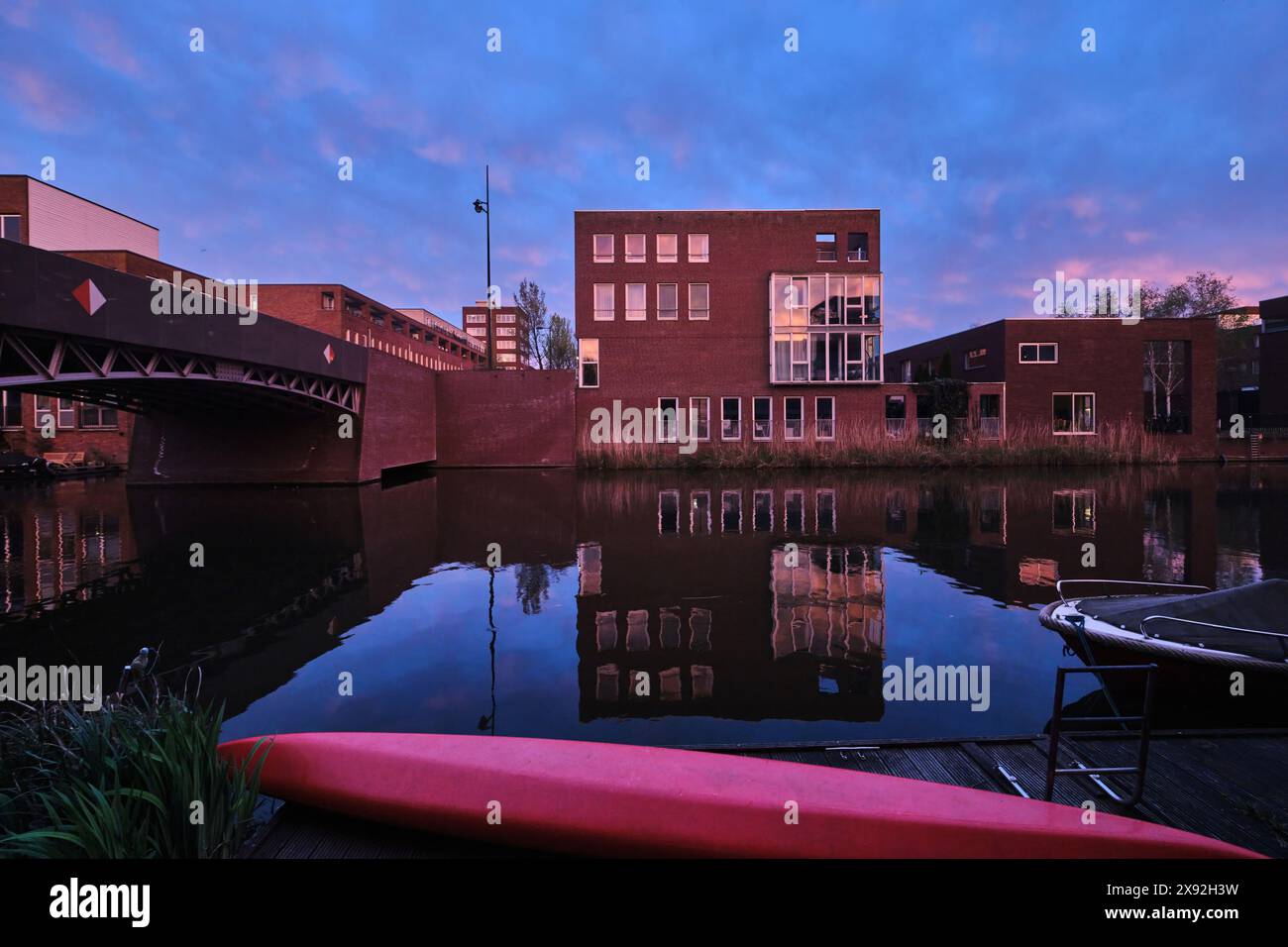 Paesi Bassi, Amsterdam - 10 aprile 2024: Edifici residenziali e architettura moderna in mattoni con vista sul canale nel quartiere di Ijburg al crepuscolo Foto Stock