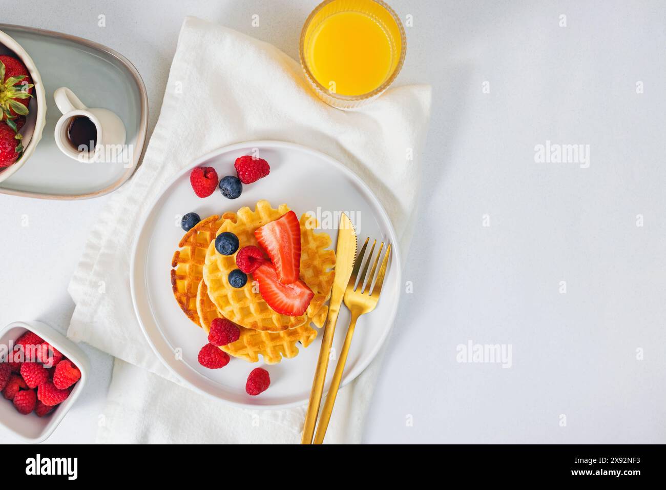 Waffle dolci fatti in casa serviti con frutti di bosco e sciroppo d'acero, vista dall'alto Foto Stock