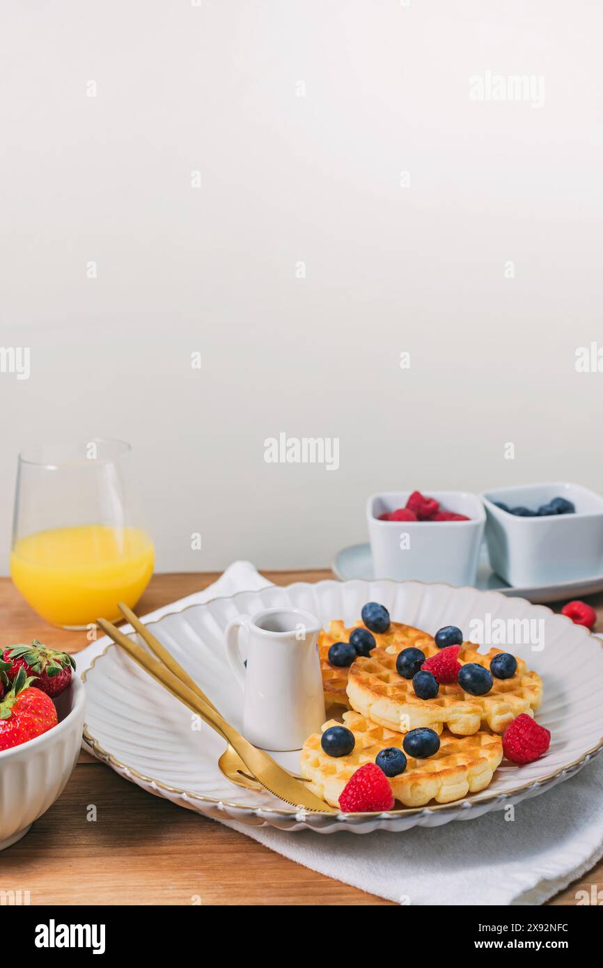 Colazione deliziosa con waffle e frutti di bosco sul tavolo di legno, vista ravvicinata Foto Stock