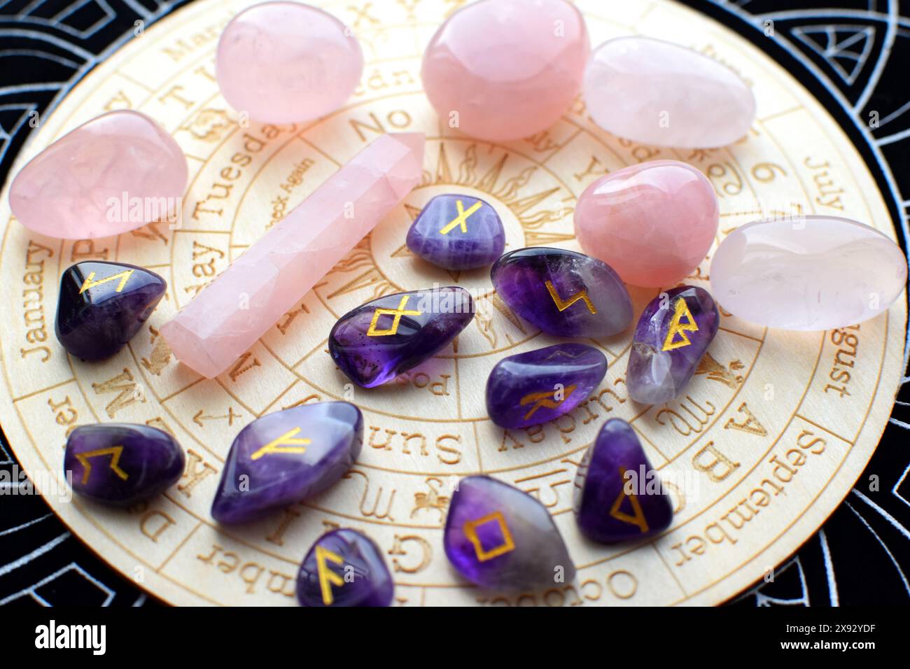 Rune scandinave fatte di ametista e cristalli di quarzo rosa su una tavola con simboli dei segni zodiacali. Previsioni, stregoneria, esoterico spirituale Foto Stock