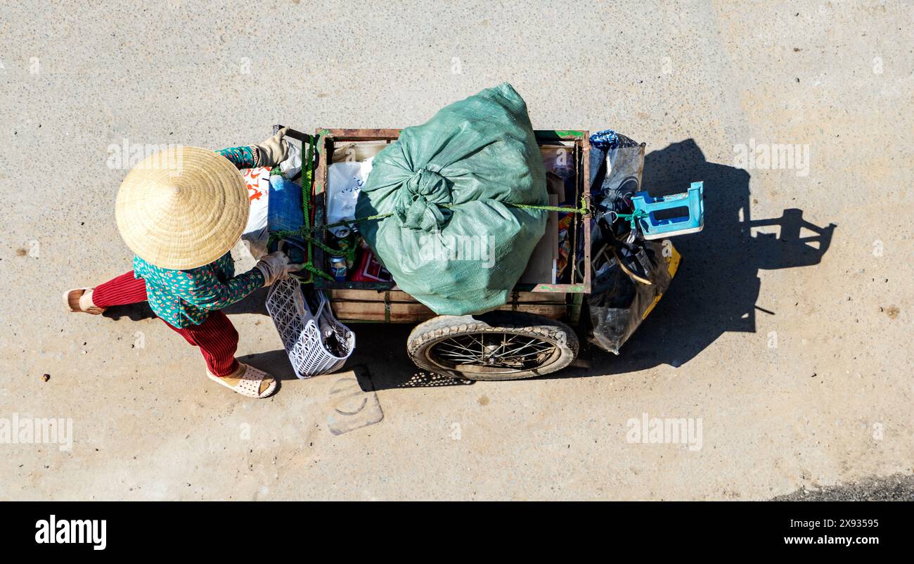 Donna vietnamita che spinge un carrello pieno di raccolta di rifiuti riciclabili, Saigon City, Vietnam. Foto Stock