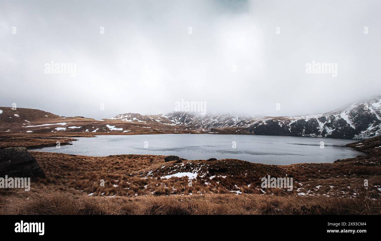 Vista del lago Sylvester, circondato dalle montagne innevate e dalla nebbia nevosa, il parco nazionale di Kahurangi Foto Stock