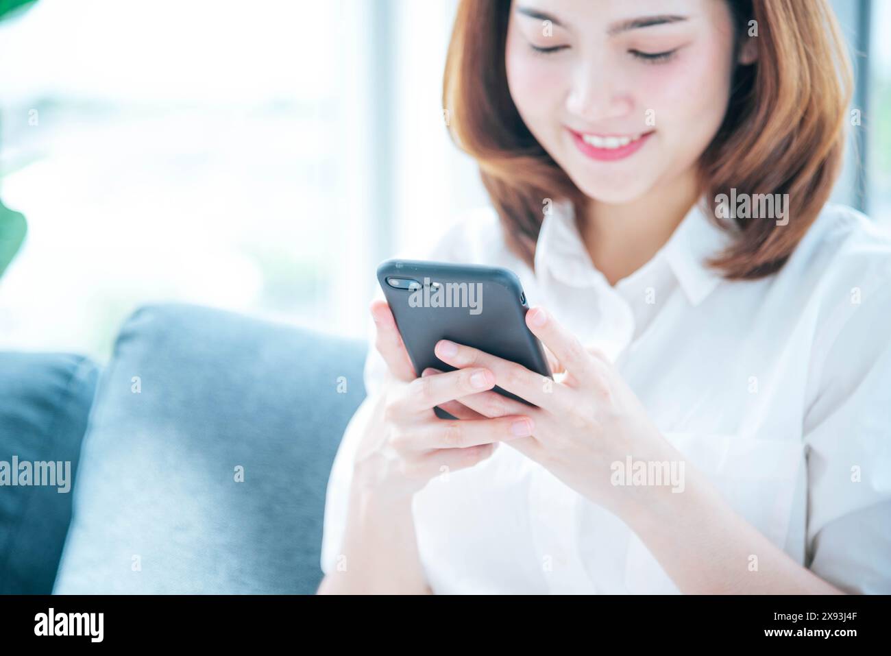 Donna asiatica che usa lo smartphone che legge i social media online che fanno shopping online sito web su smartphone con la faccia del sorriso. Felicità donna asiatica che tiene il cellfone Foto Stock