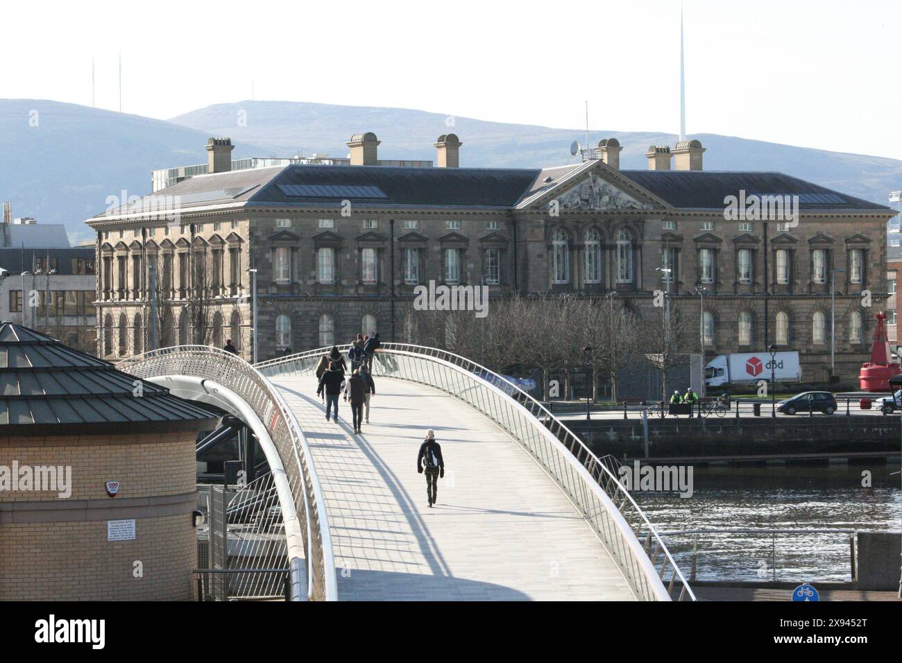 Pedoni che camminano attraverso il ponte pedonale Lagan Weir a Belfast in un pomeriggio di sole. Foto Stock