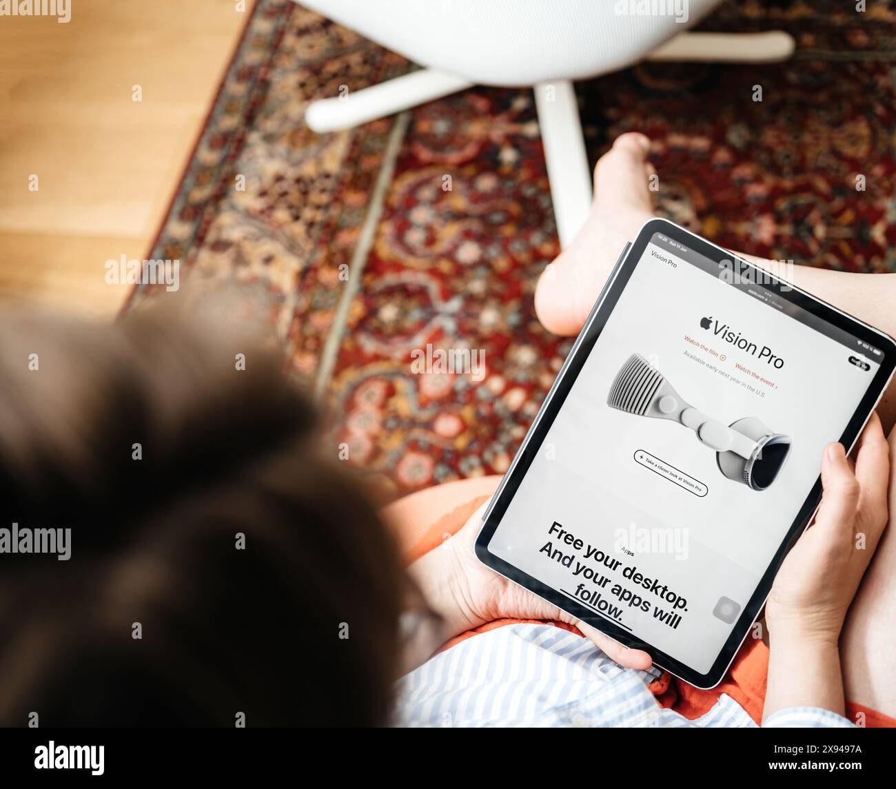 Parigi, Francia - 11 giugno 2023: Una donna è seduta e sta navigando sul sito Web di Apple su un iPad, visualizzando la pagina del prodotto Vision Pro con lo slogan libera il tuo desktop. E le applicazioni seguiranno. Foto Stock