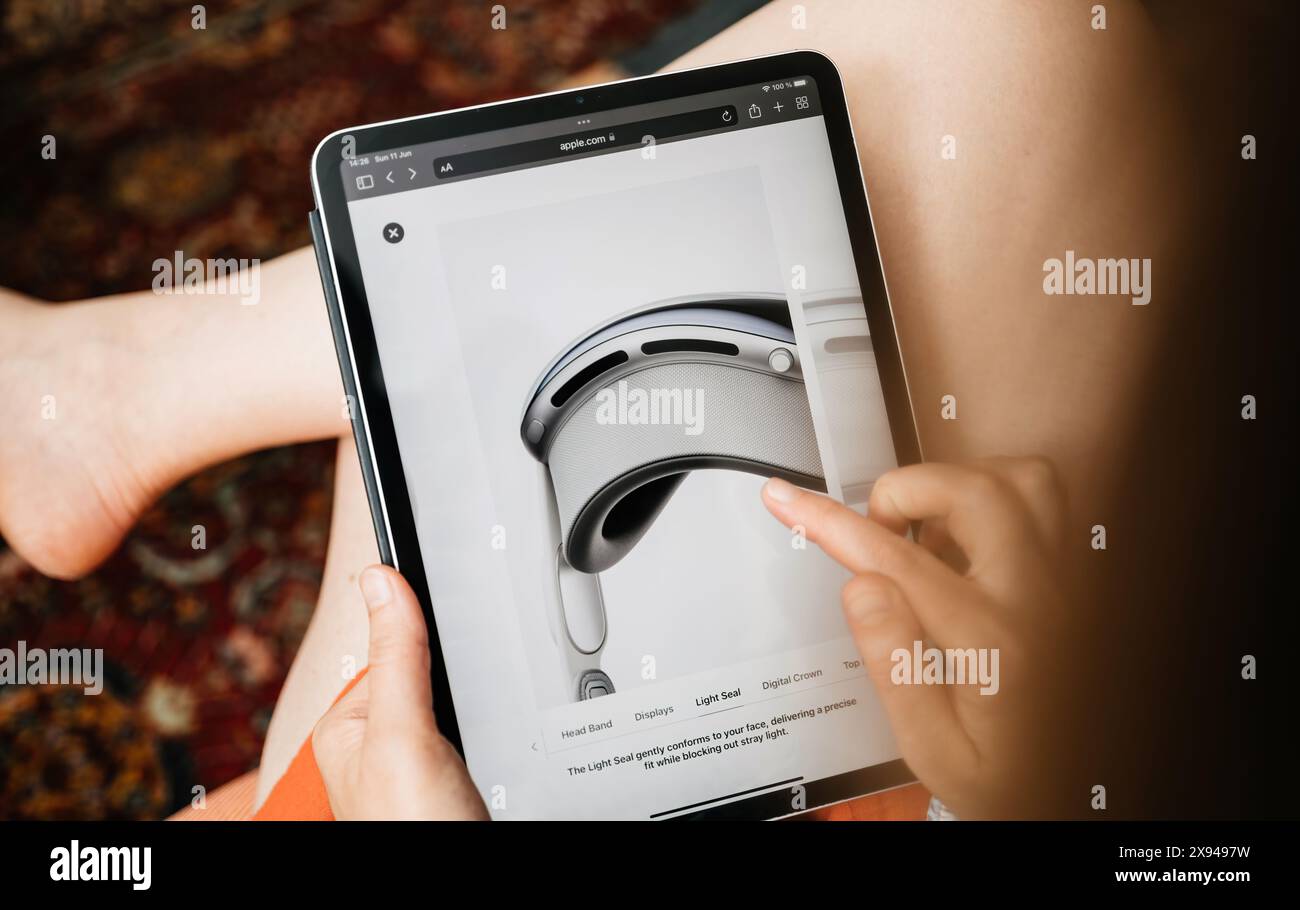 Parigi, Francia - 11 giugno 2023: Una donna sta visitando un sito Web Apple su un iPad, concentrandosi sui dettagli di una cuffia Vision Pro, con il dito rivolto verso la descrizione del sigillo luminoso sullo schermo Foto Stock