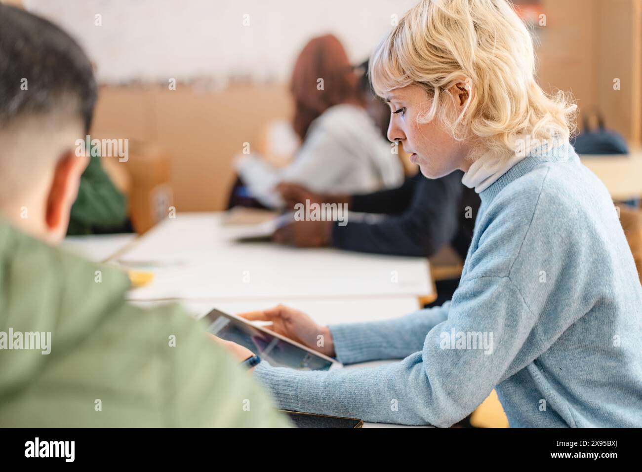 Studente universitario concentrato che studia con un tablet in classe - concentrazione, istruzione moderna e coinvolgimento accademico, con lo studente profondamente invo Foto Stock