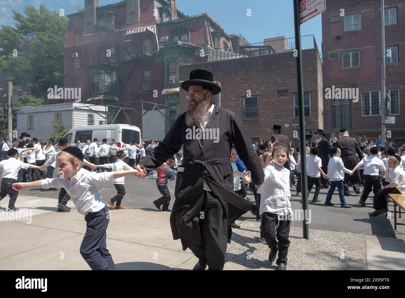 Un rabbino e i suoi allievi ballano a una celebrazione del LAG B'Omer in una strada chiusa a Williamsburg, Brooklyn, New York. Foto Stock