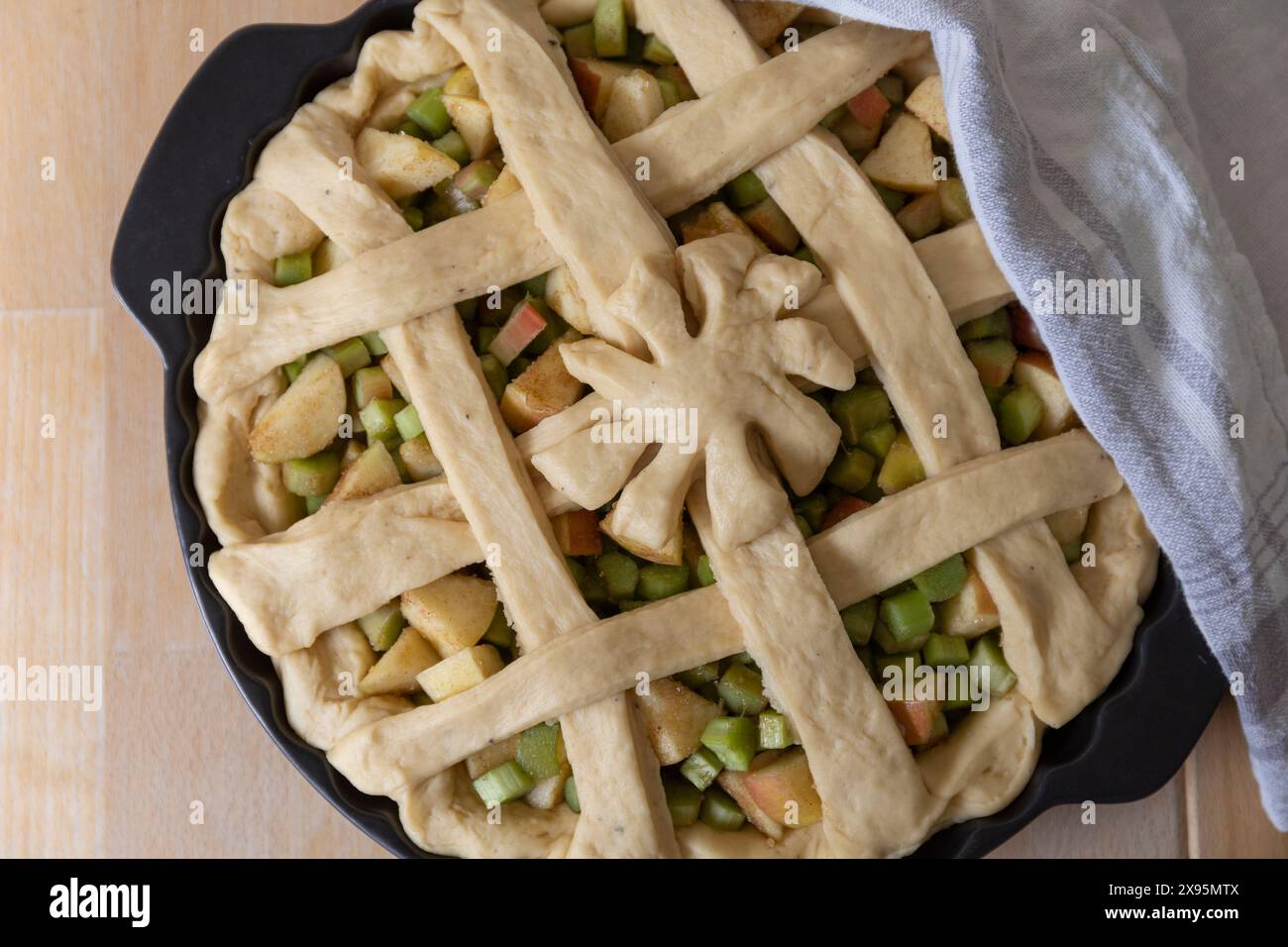 Fotografia di cibo da tavolo di lievito aperto, rabarbaro e torta di mele, pronti per la cottura, con un supporto rotondo in ceramica nera, in piedi su un tavolo di legno Foto Stock