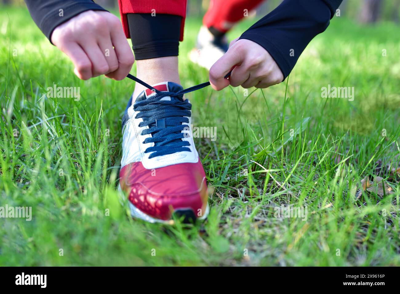 Una donna lega i lacci alle sue sneakers nel parco Foto Stock