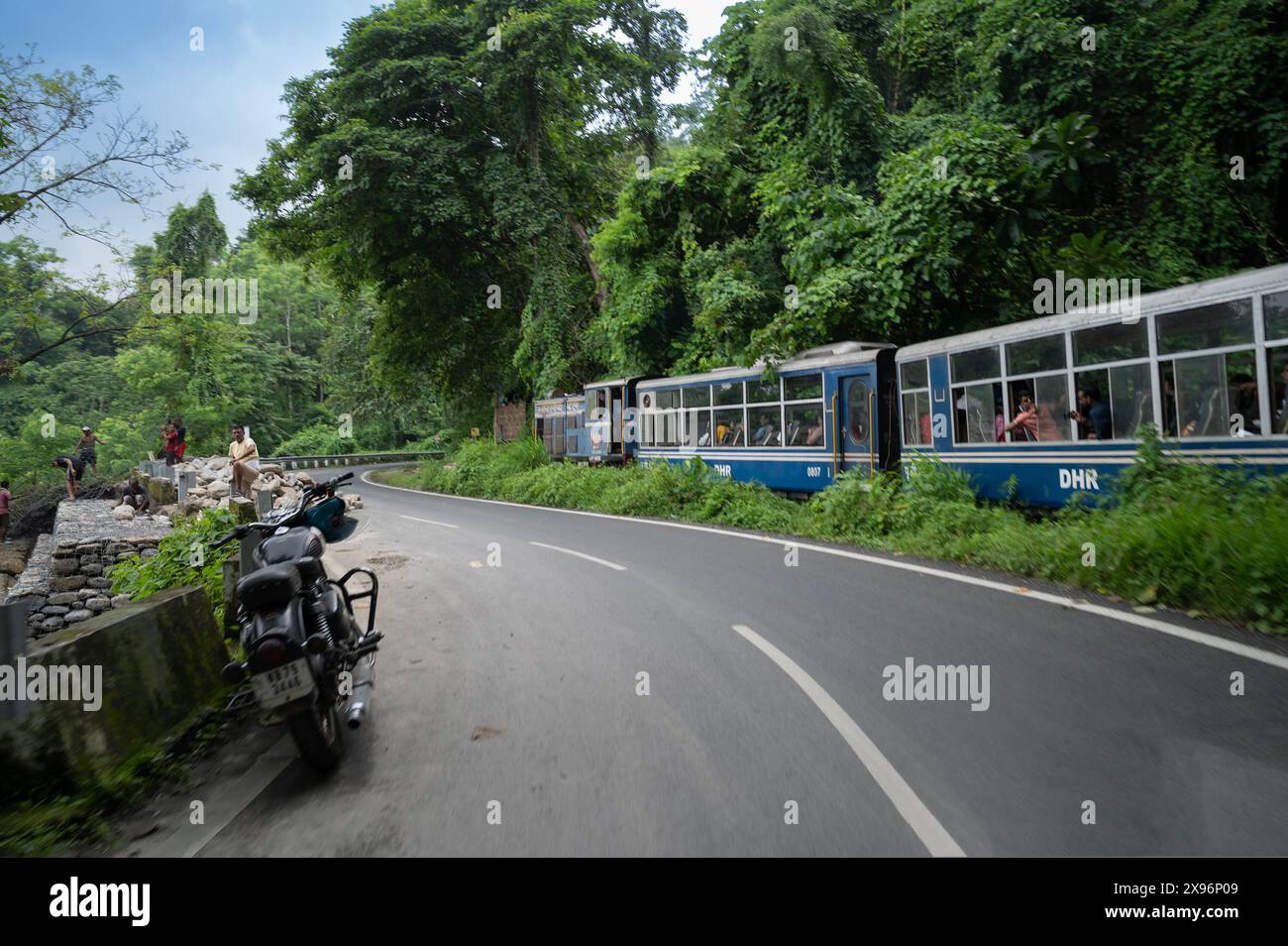Darjeeling, Bengala Occidentale, India - 10 agosto 2023: La strada himalayana è stata costruita dai lavoratori, mentre il treno Diesel Toy passa attraverso la giungla accanto. Foto Stock