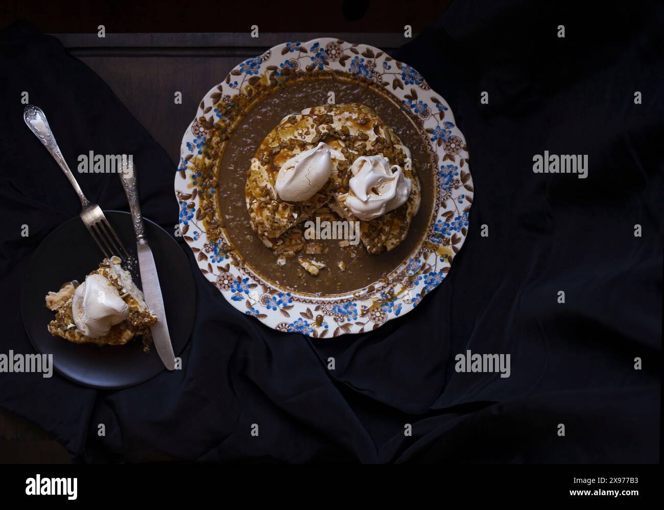 Foto da tavolo della torta Pavlova con salsa di caffè e noci su un piatto vintage in porcellana inglese con motivo floreale blu e marrone Foto Stock