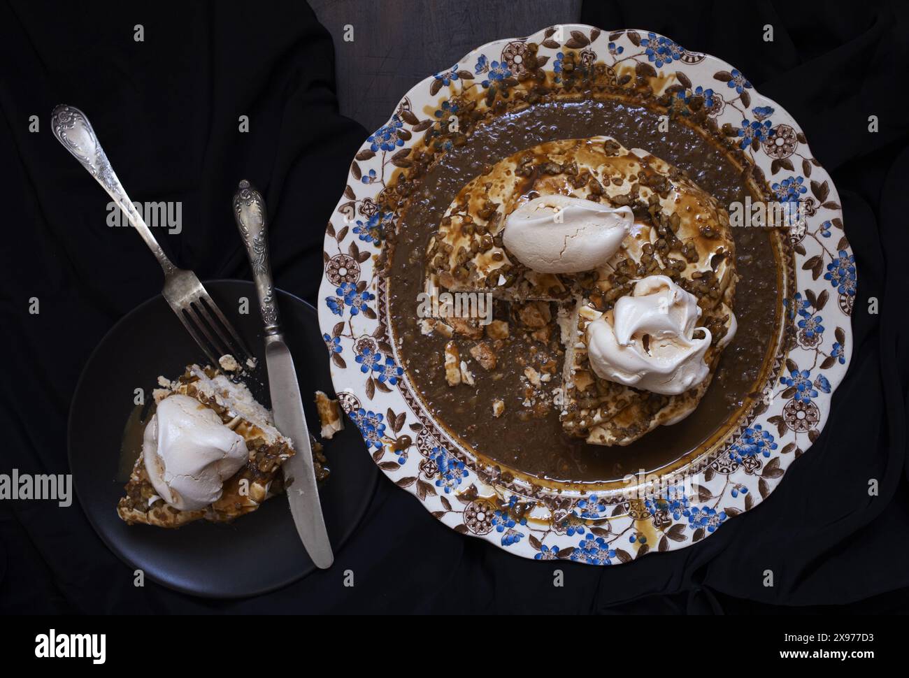 Foto da tavolo della torta Pavlova con salsa di caffè e noci su un piatto vintage in porcellana inglese con motivo floreale blu e marrone Foto Stock
