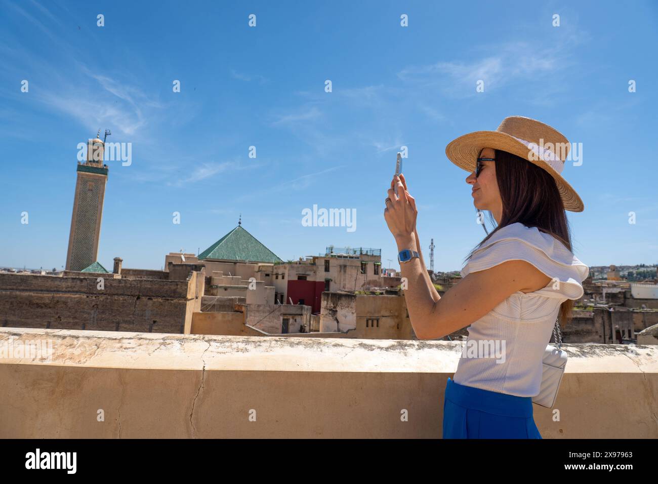 Giovane donna in cappello che fotografa il paesaggio urbano di Fez con smartphone, Marocco Foto Stock