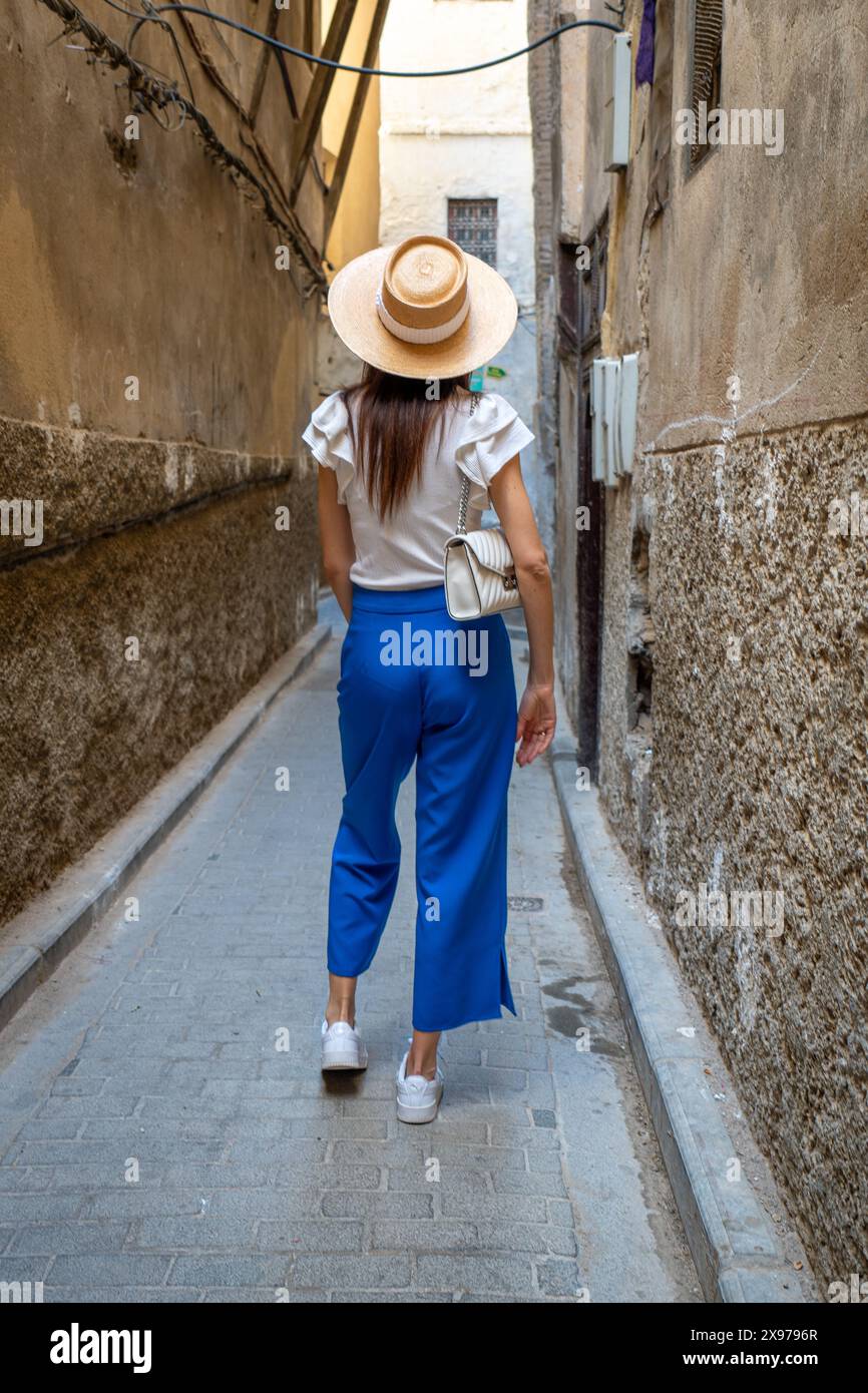 Giovane donna in cappello passeggiando per le strade di Fez, Marocco Foto Stock