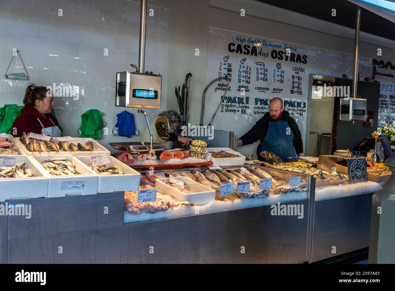 Oporto, Portogallo - 23 novembre 2023: Pescivendoli nel negozio di pesce con ostriche fresche e pesce in un negozio di pesce gourmet nel mercato di Bolhao, cibo di strada ma Foto Stock