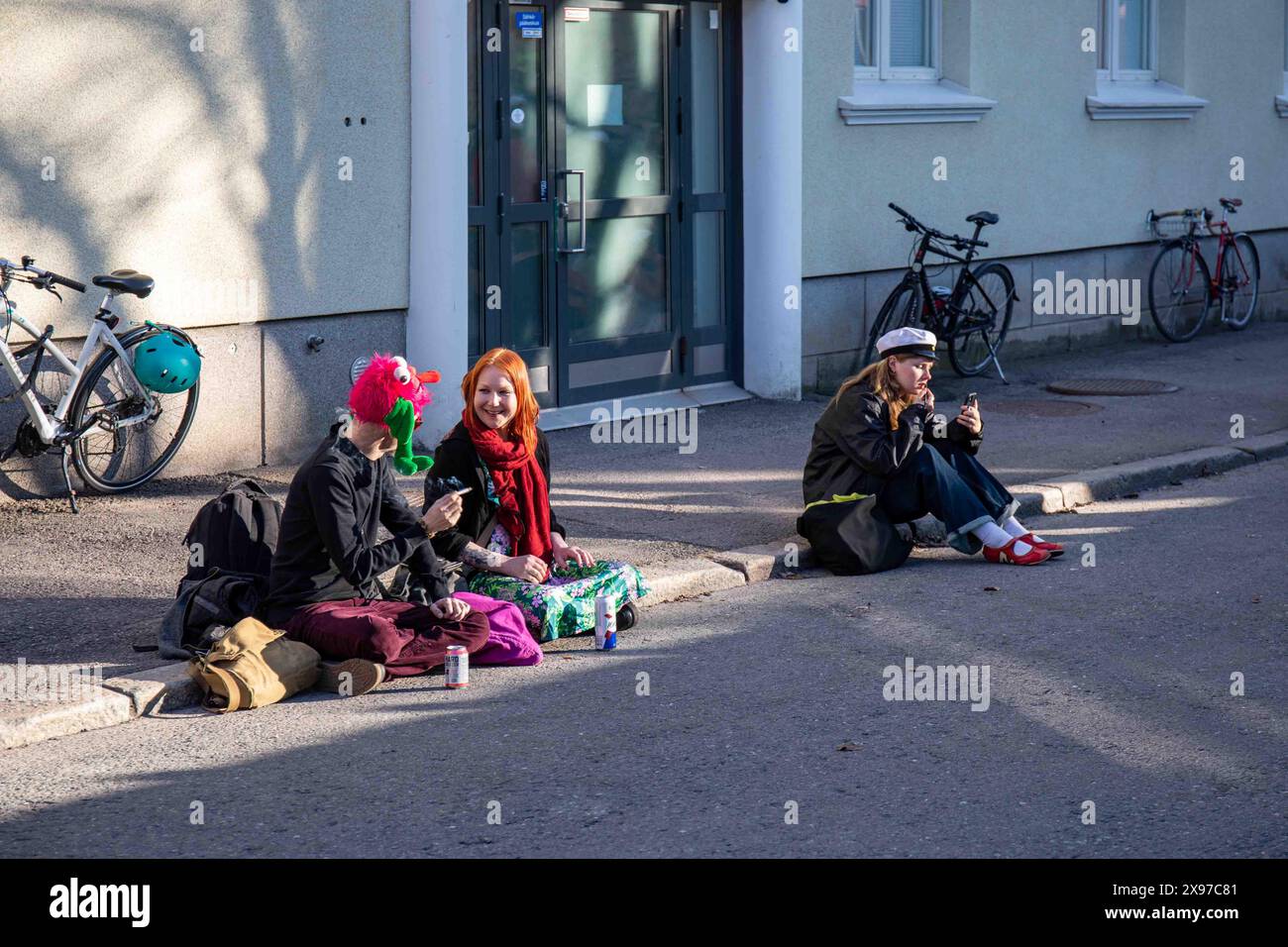 Giovani seduti a bordo di un marciapiede la vigilia di maggio nel quartiere di Vallila a Helsinki, Finlandia Foto Stock