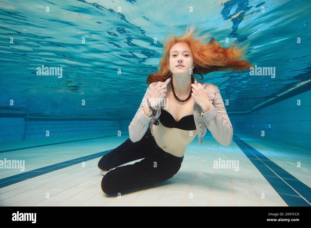 Una giovane donna con vestiti che si tuffano sott'acqua in una vasca da bagno Foto Stock