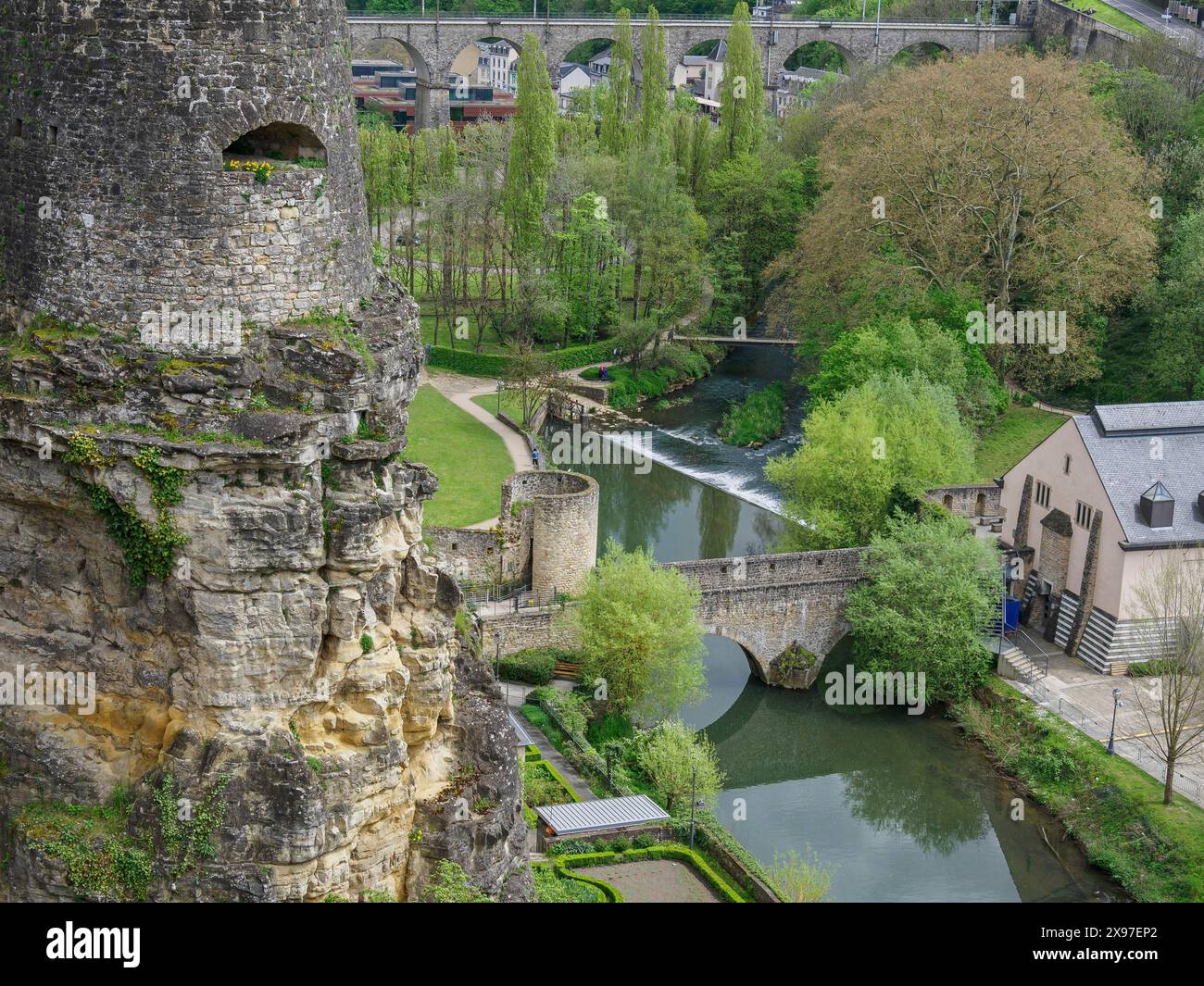Castello storico e ponte su un fiume, circondato dalla vegetazione verde in primavera, che si affaccia su un quartiere storico di una grande città di mare con Foto Stock