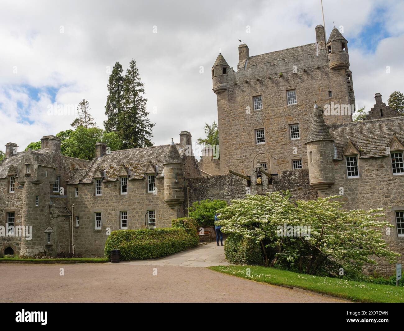 Castello storico con torri e vegetazione verde sotto un cielo nuvoloso, vecchio edificio in pietra grigia in un grande giardino con molto verde, Invergordon Foto Stock