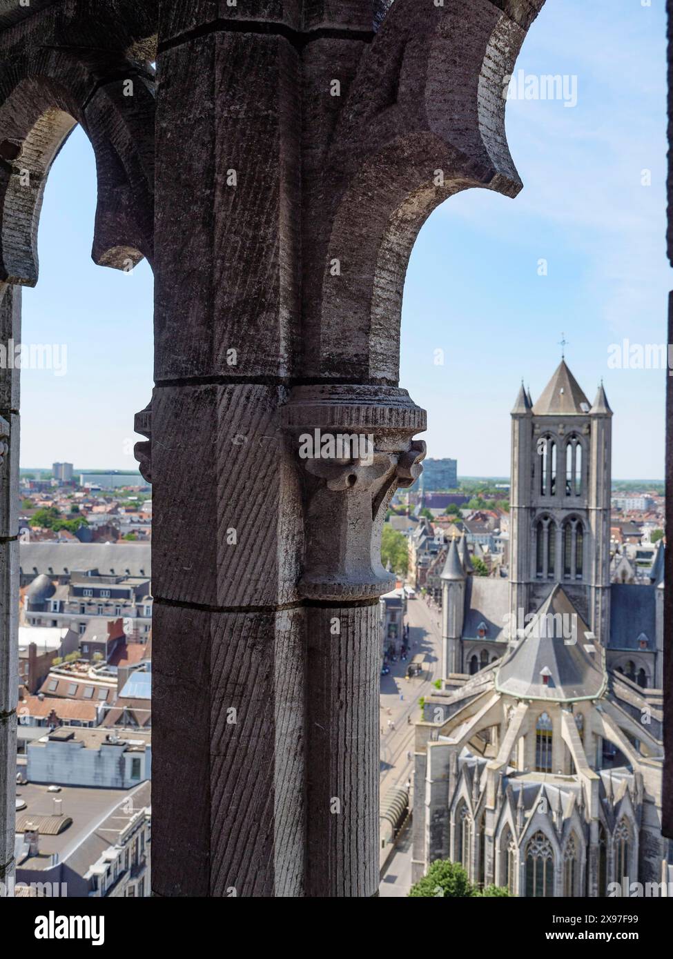 Ammira attraverso un arco gotico una cattedrale e il paesaggio urbano dietro di essa in una giornata di sole, la città medievale con chiese e edifici storici visti da Foto Stock