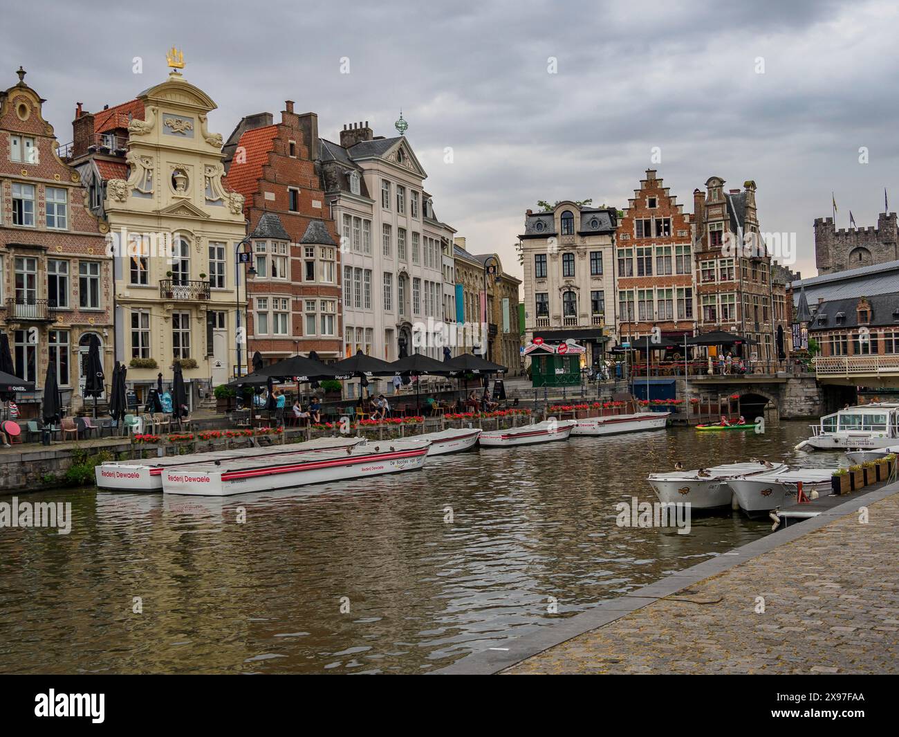 Scena cittadina con edifici storici lungo un canale, barche e un cielo nuvoloso, skyline di una città storica sul fiume con facciate antiche e bellissime Foto Stock