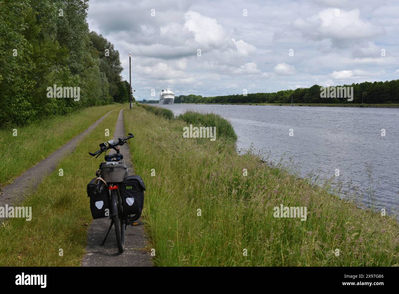 Pedalando lungo il canale di Kiel con vista su una nave da crociera, Schleswig-Holstein, Germania Foto Stock