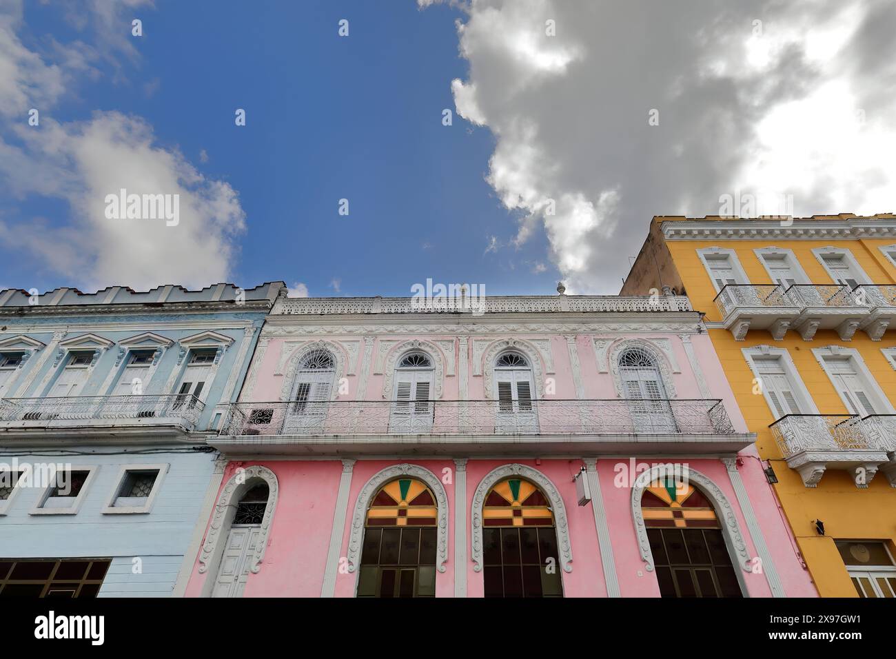 326 edifici coloniali rivolti a ovest dipinti di giallo zafferano azzurro pallido, rosa, sul lato est del Parque Serafin Sanchez Park. Sancti Spiritus-Cuba. Foto Stock