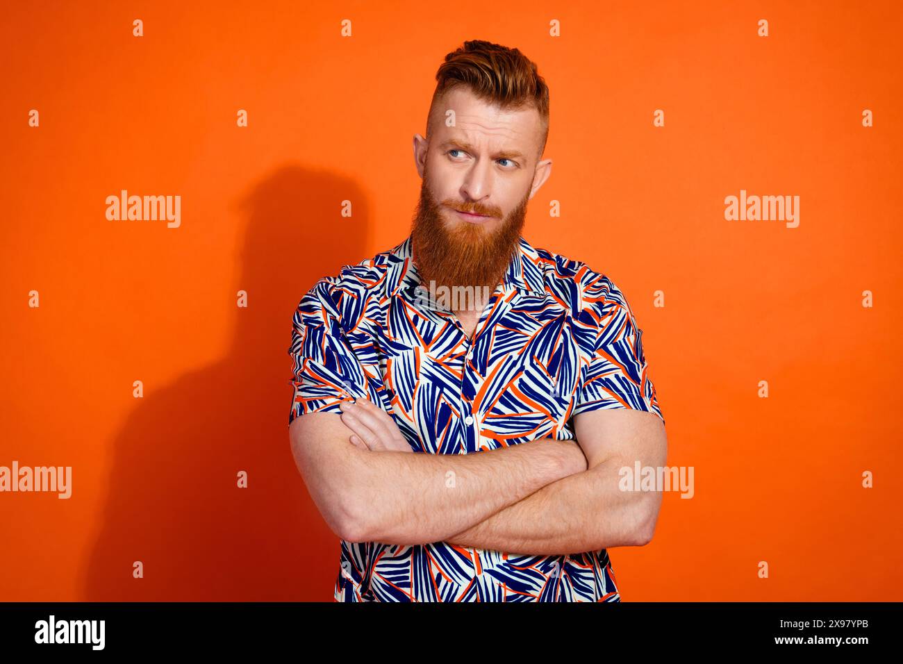 Ritratto di un uomo brutale e cool indossa le braccia della camicia stampate uno spazio vuoto a prezzi scontati isolato su sfondo arancione vivace Foto Stock