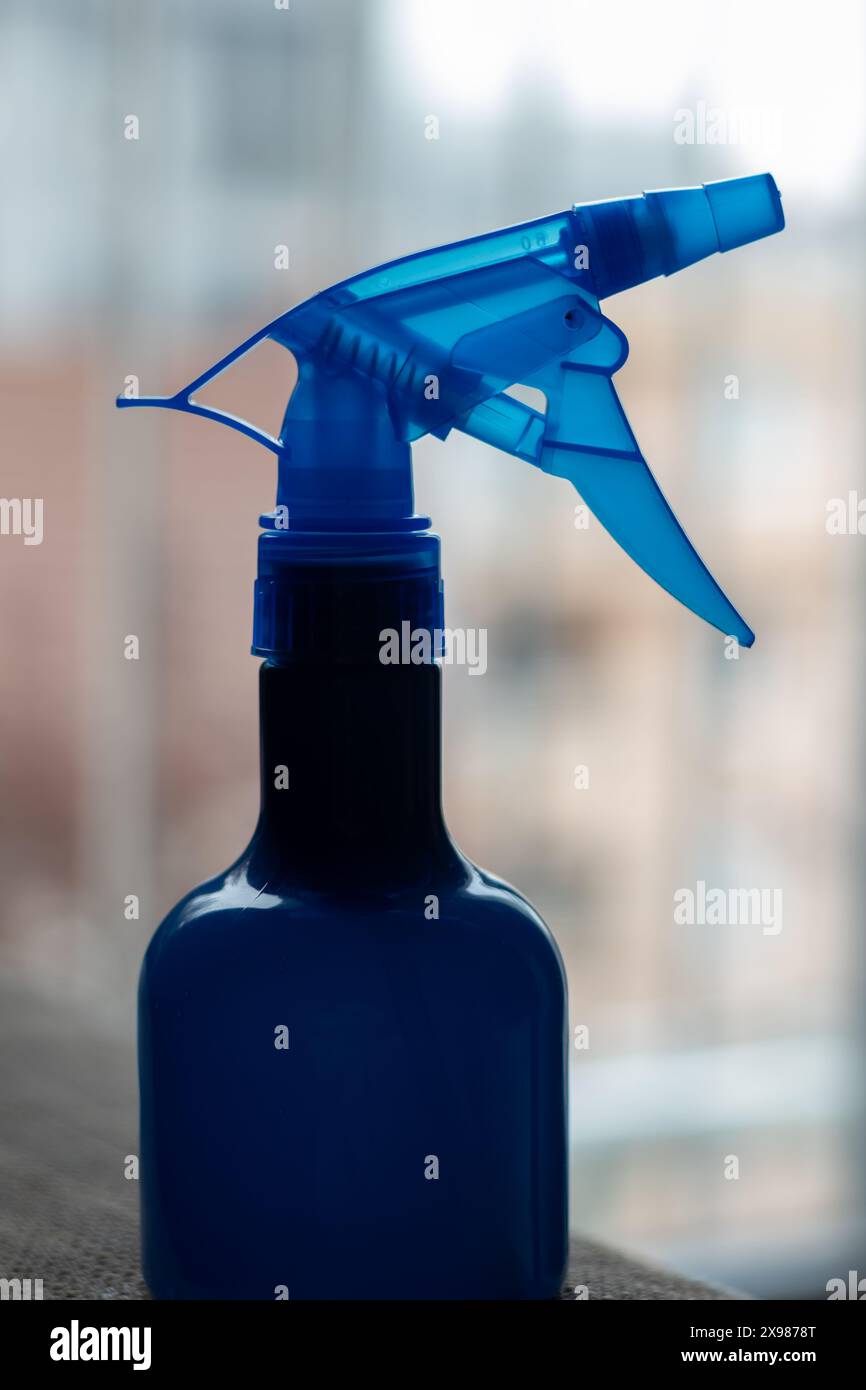 Primo piano di una bottiglia spray blu con sfondo sfocato, ideale per la pulizia o il giardinaggio. Foto Stock