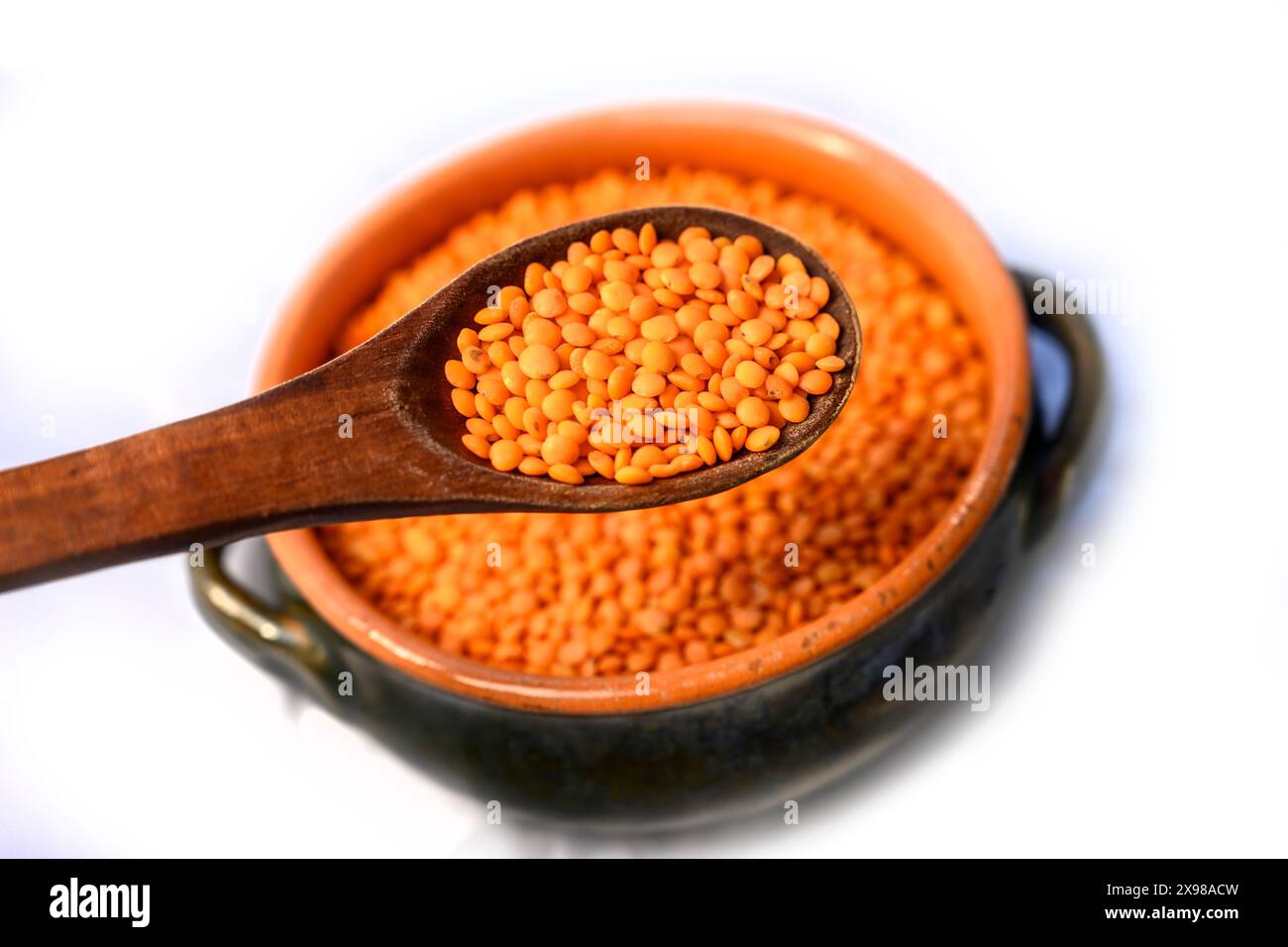 contiene lenticchie rosse e cucchiaio di legno che le solleva Foto Stock