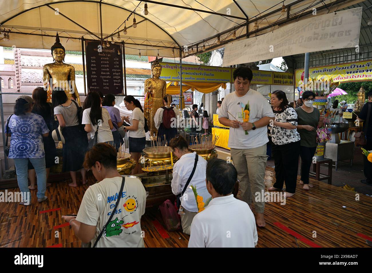 Persone che fanno offerte di fiori di calendula e incenso il giorno Vesak 2024, al Wat Phra Pathommachedi Ratcha Wora Maha Wihan, Nakhon Pathom, Thailandia Foto Stock