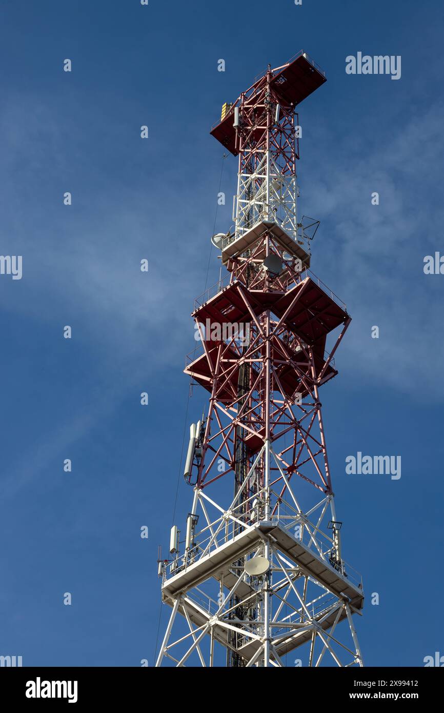 Antenna per telecomunicazioni per radio, televisione e telefonia con nuvola e cielo blu. Foto Stock