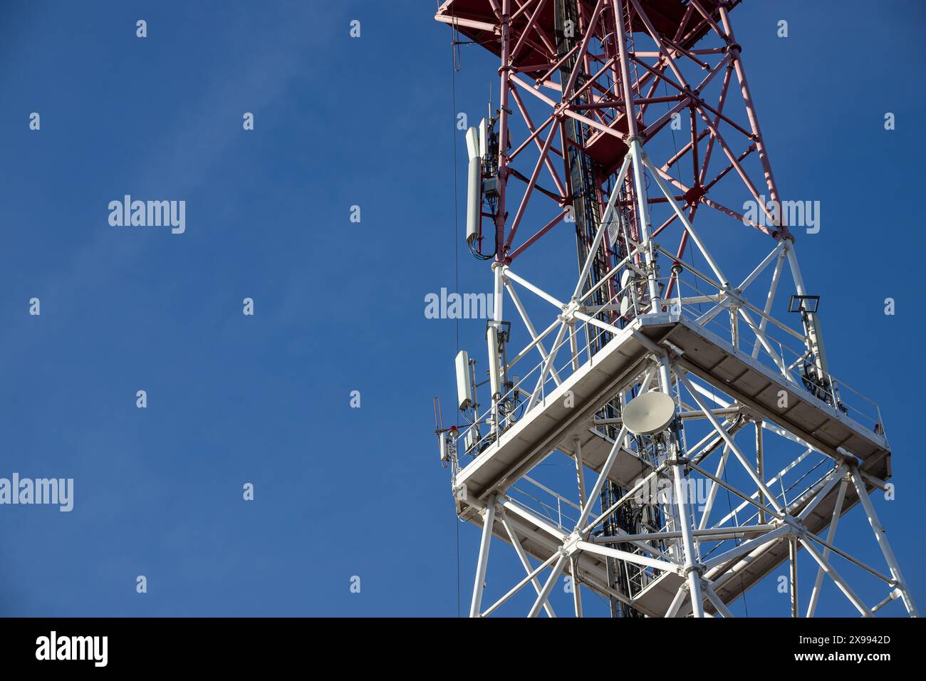 Antenna per telecomunicazioni per radio, televisione e telefonia con nuvola e cielo blu. Foto Stock