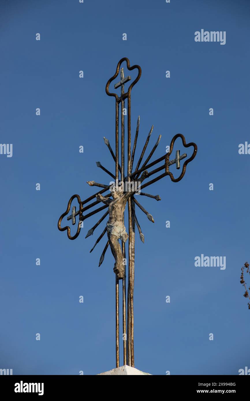 Vecchia croce di metallo con un crocifisso su uno sfondo cielo senza nuvole. Immagine verticale. Foto Stock
