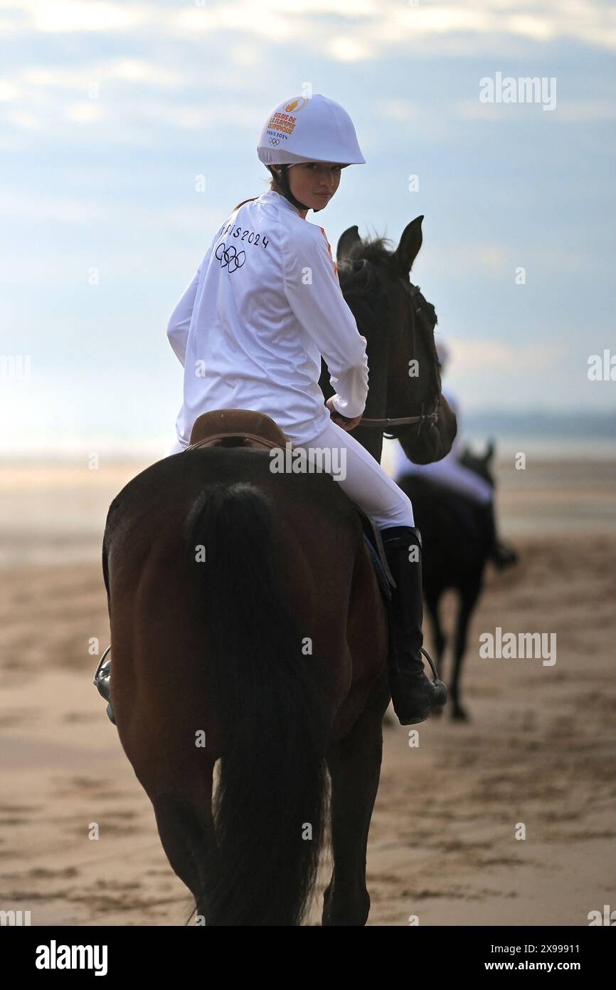 Saint Laurent Sur Mer, Gabon. 29 maggio 2024. Il 30 maggio il pilota francese di salto ostacoli e campione olimpico Penelope Leprevost porta la fiamma olimpica a cavallo, fiancheggiata da gendarmi a cavallo, durante la staffetta olimpica della squadra equestre, in vista dei Giochi olimpici e paraolimpici di Parigi 2024, sulla spiaggia di Omaha, Saint-Laurent-sur-Mer, Francia nordoccidentale, 2024. foto di Franck Castel/ABACAPRESS. COM credito: Abaca Press/Alamy Live News Foto Stock